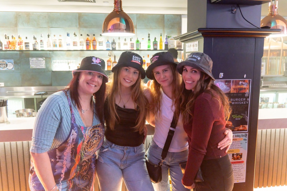 Four friends in bucket hats smiling at the bar