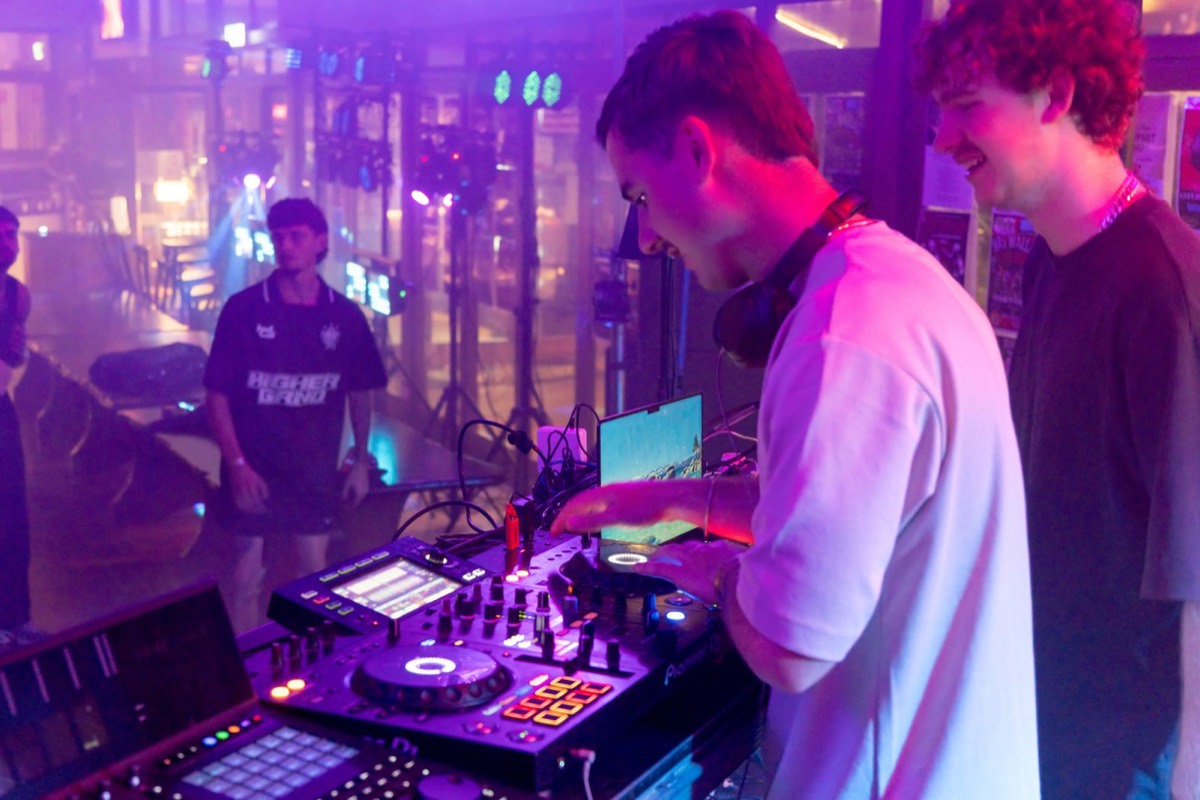 DJ mixing at the decks with friends beside the booth