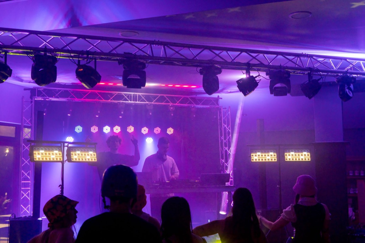 Stage with truss rig, moving-head lights and DJ at the decks under purple light