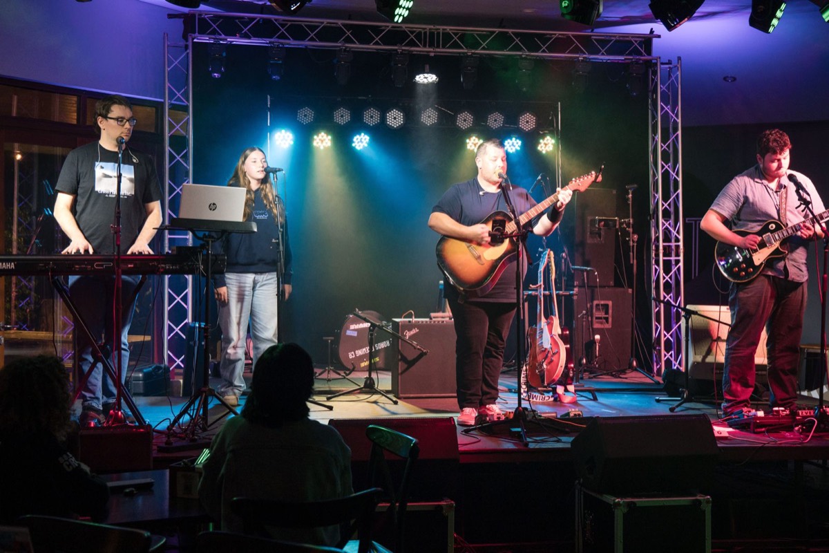 Full band on the trussed stage under coloured lights at Valley Social