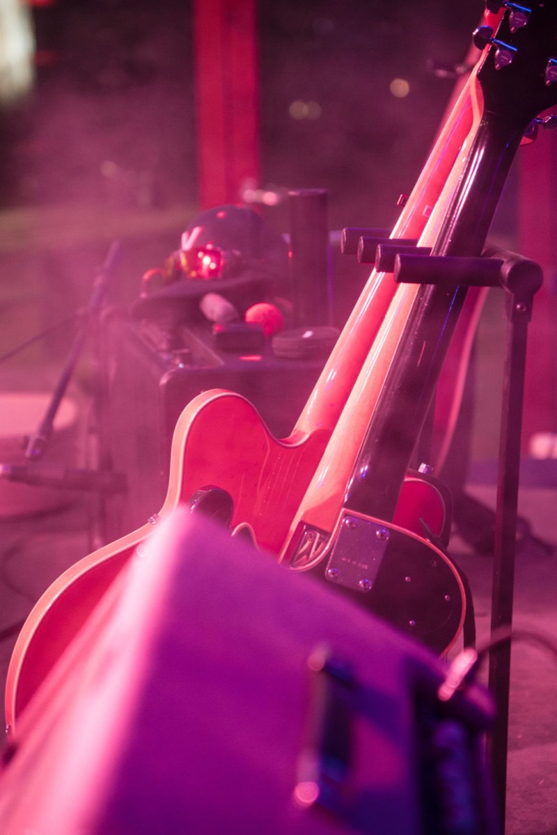 Red electric guitar resting against an amp in pink light