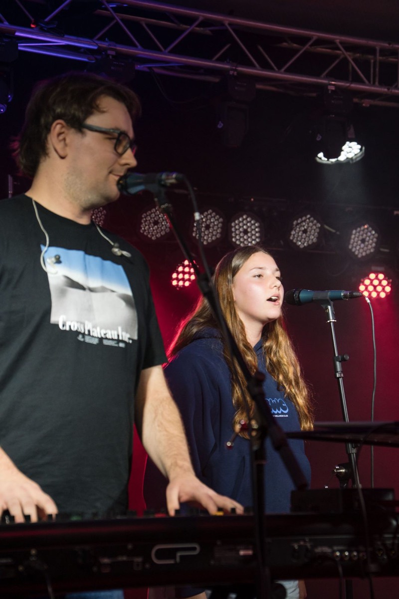 Two vocalists sharing keys under red backlight