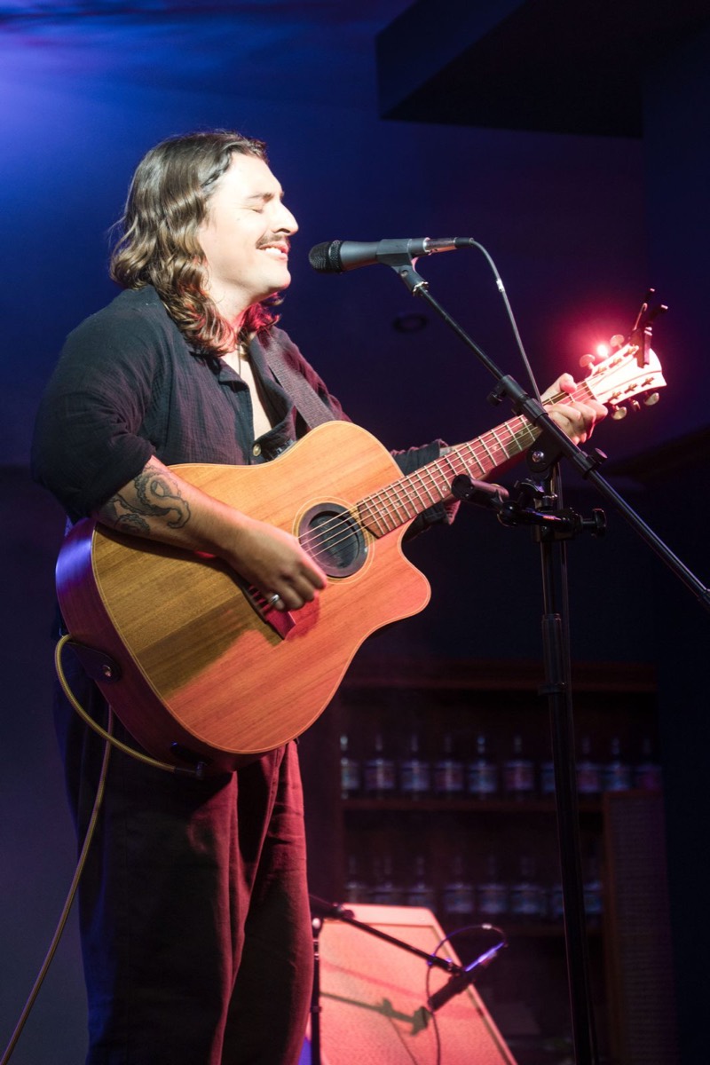 Performer laughing at the microphone with an acoustic guitar